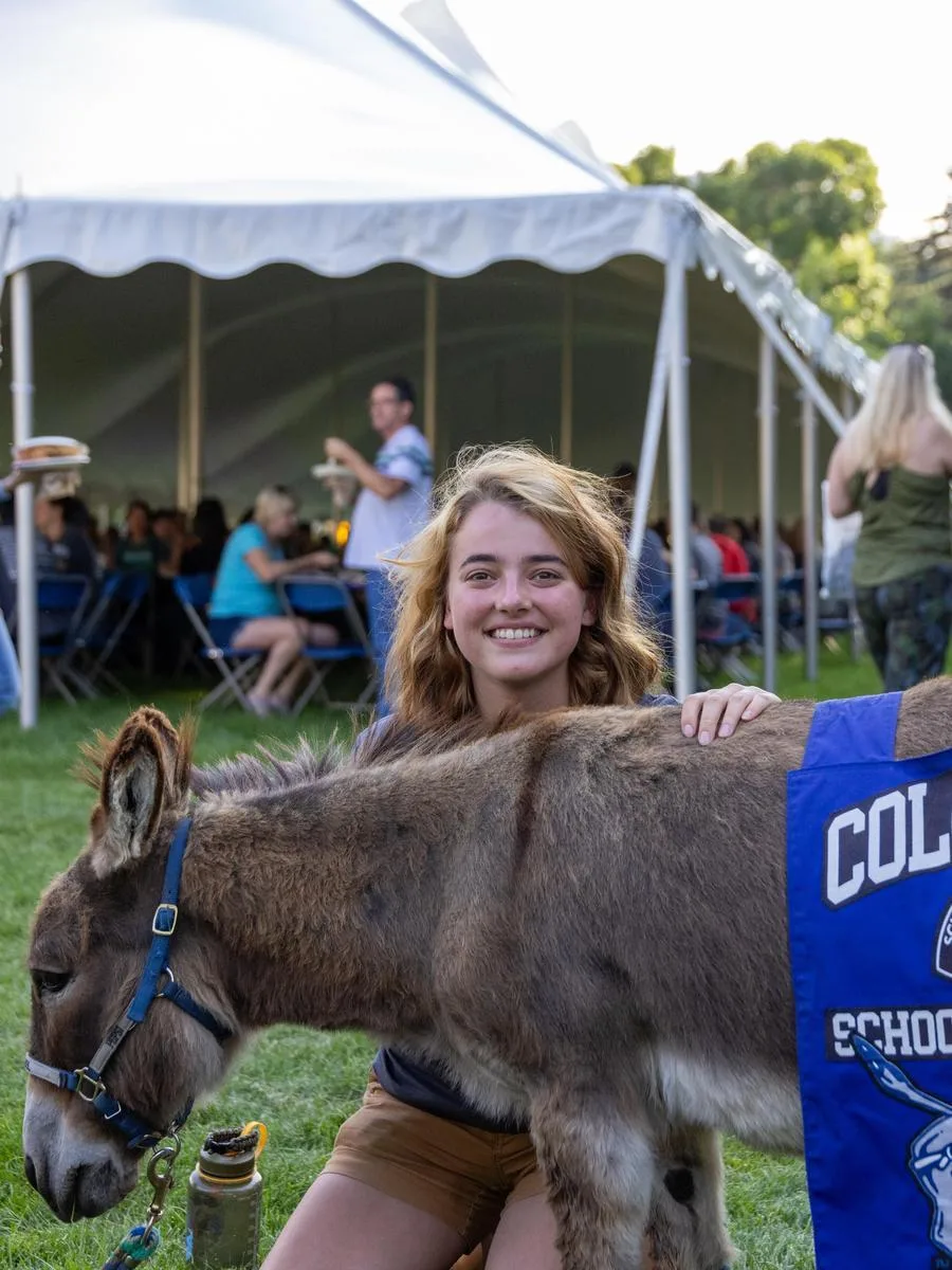Mines freshman student poses with Blaster the Burro at the Move In Day BBQ.