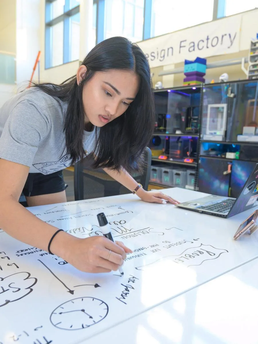 A Mines student draws out a project strategy on a white board in a design studio