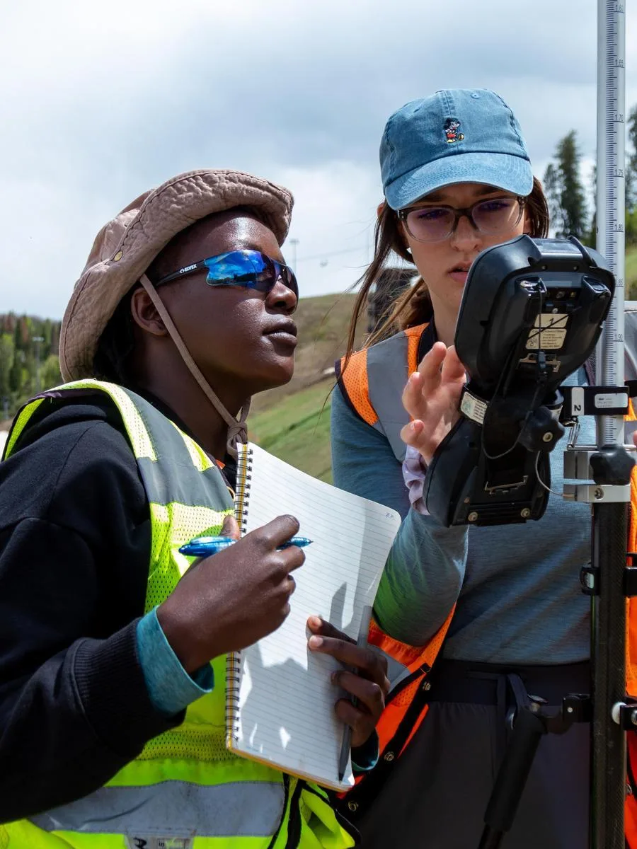Two Geophysics students take readings from a subsurface monitor in the field
