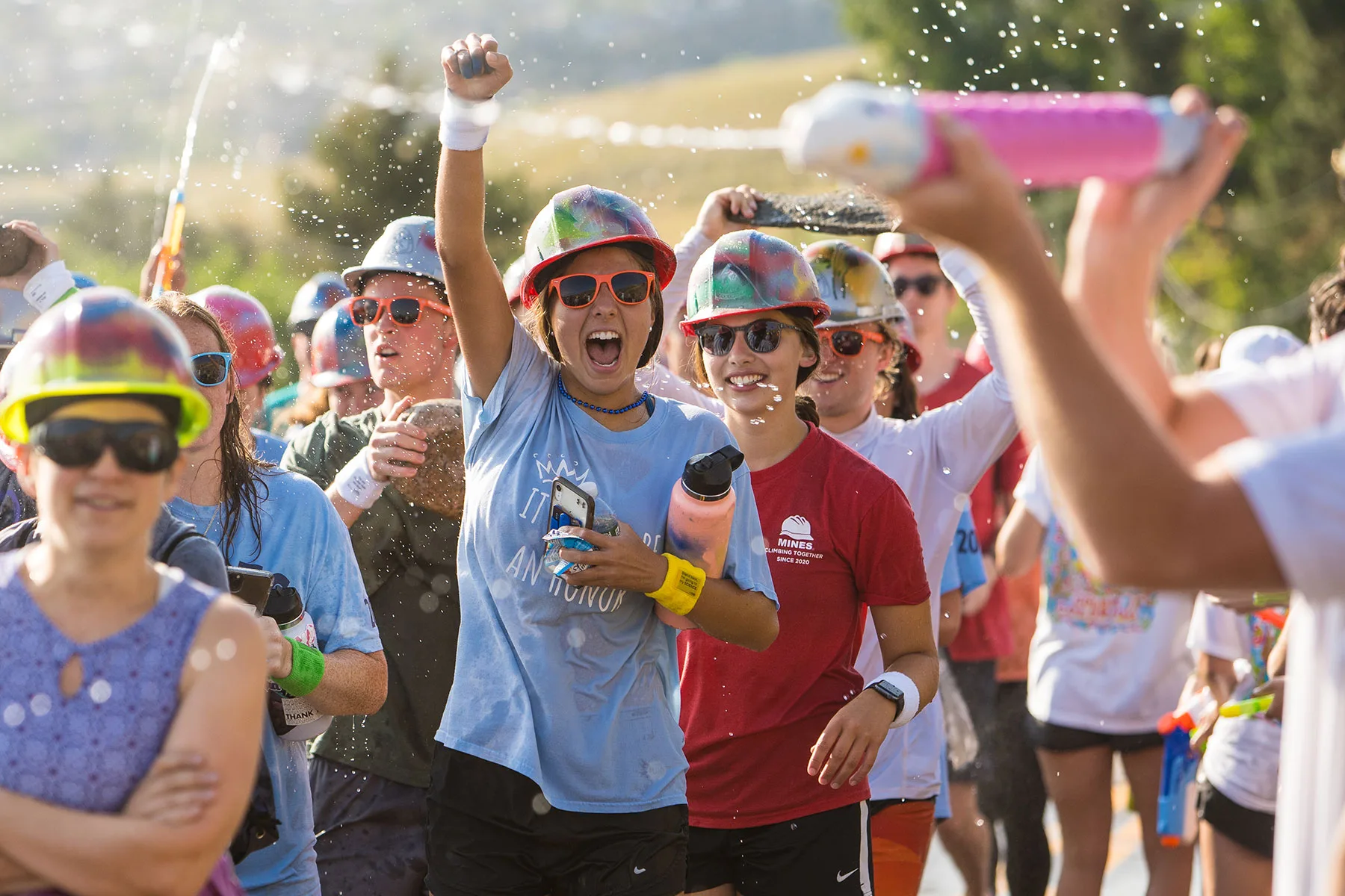 Mines students in their hard hats celebrating on the M Climb with water spraying