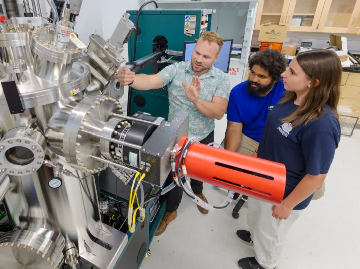 Researchers working with a thin-film deposition and surface characterization system for materials research