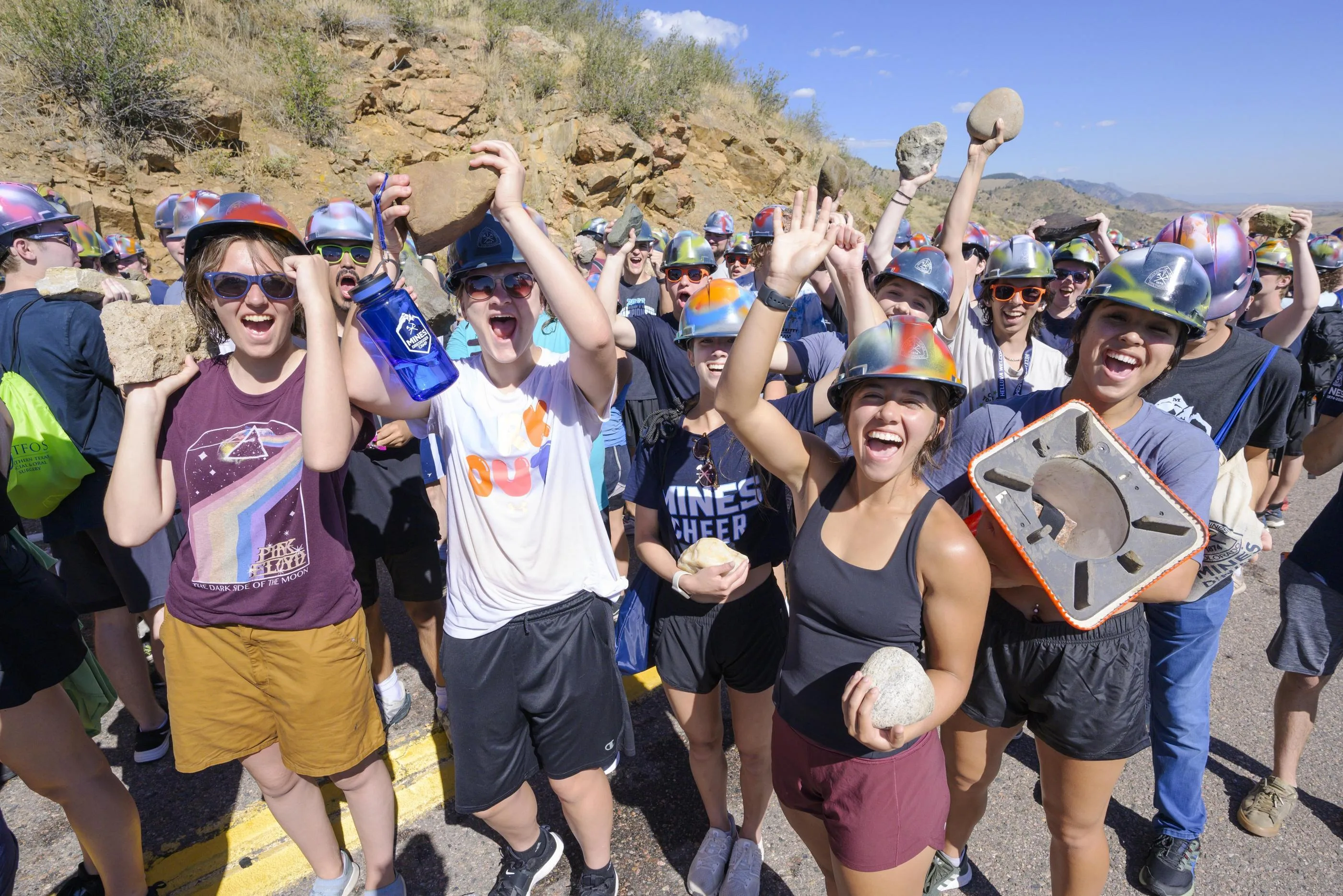 students wearing hardhats lift rocks during m climb