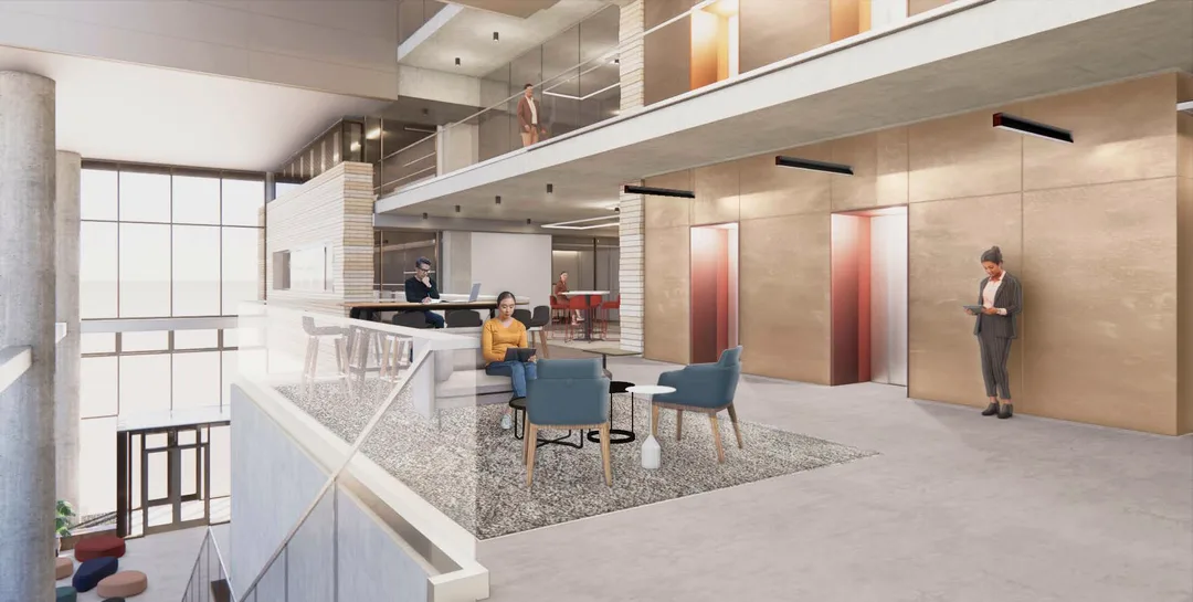 Modern office lounge with people working on laptops and tablets near elevators and a seating area with chairs and tables.