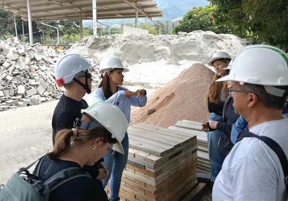 A group of people wearing hard hats listens to a speaker on site in Colombia talk about concrete waste