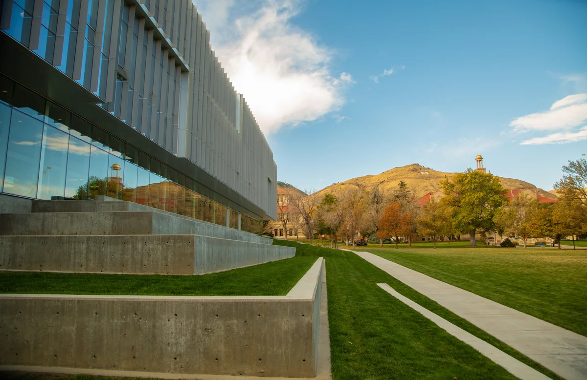 View from CoorsTek Center's steps across a fall campus lawn toward Guggenheim Hall's tower and the 