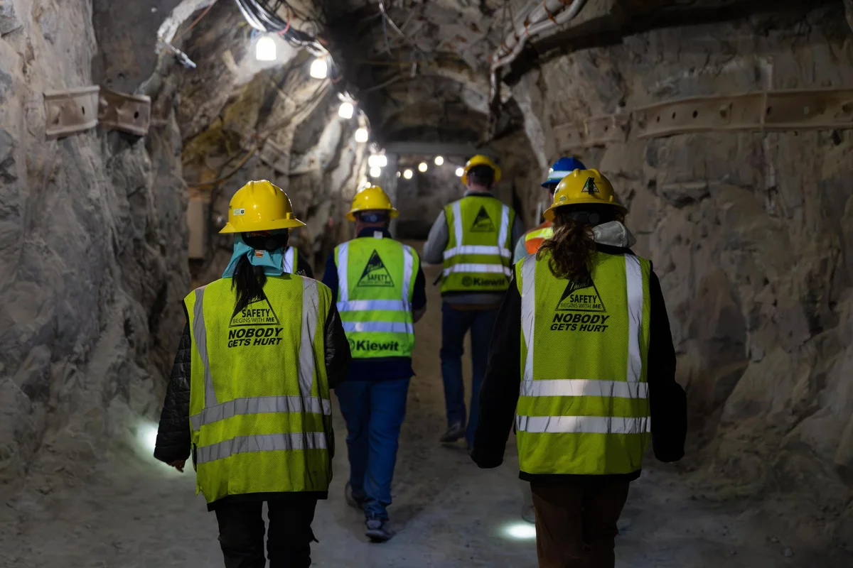 Students in yellow safety gear walk through a mine tunnel