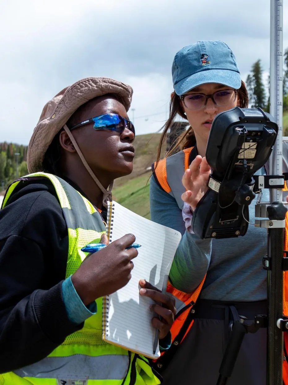 Two Geophysics students take readings from a subsurface monitor in the field