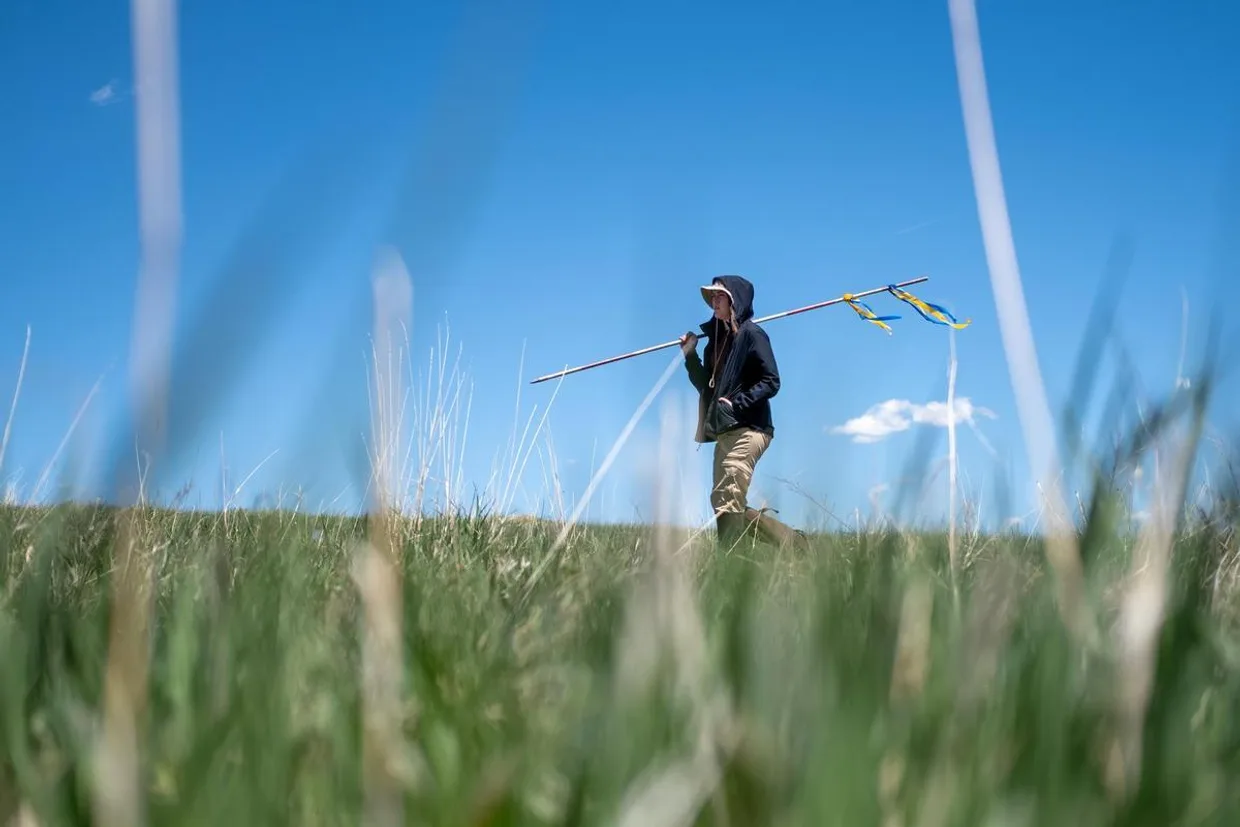 Mines student walking through open field with equipment for monitoring environmental data