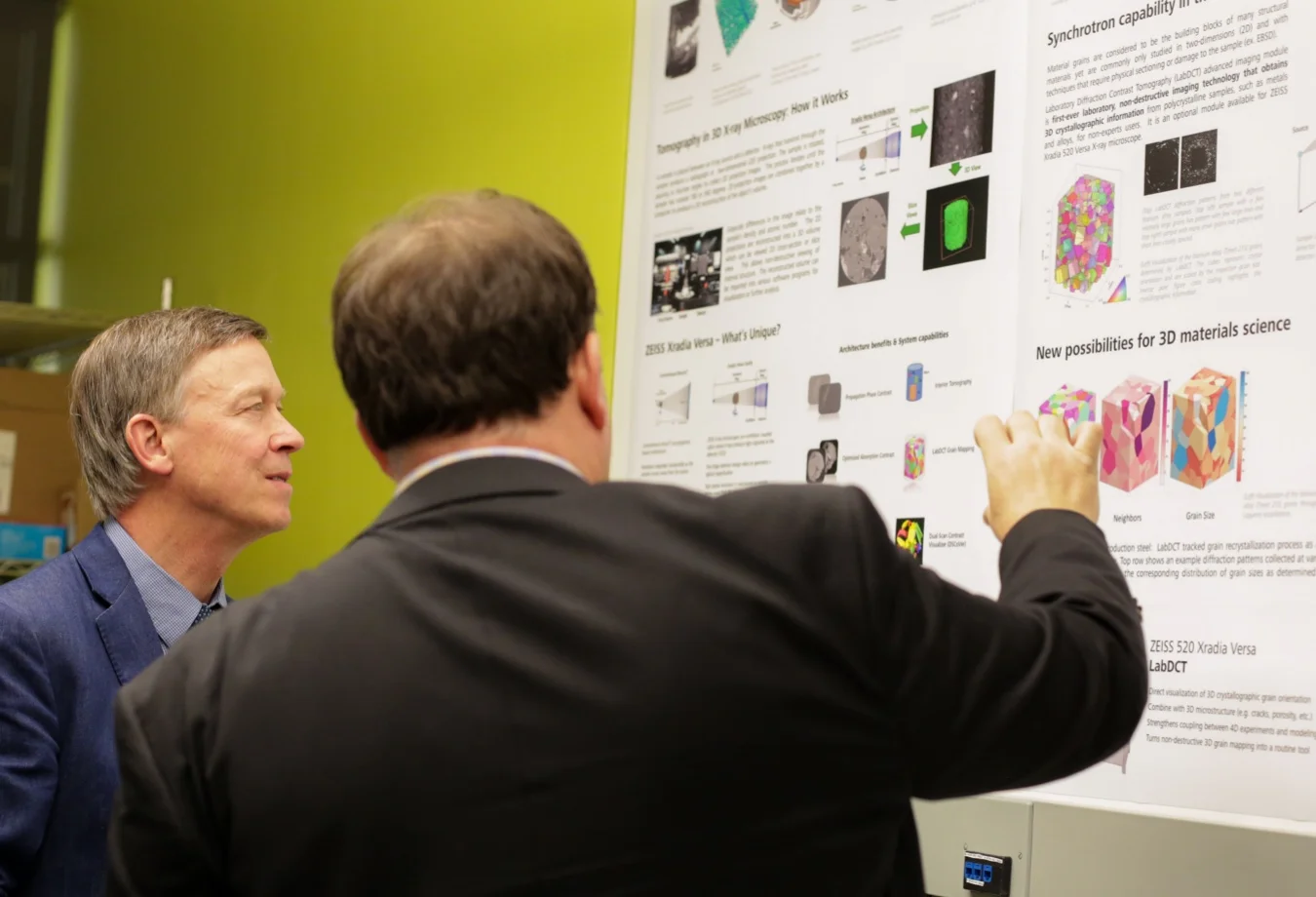 This image shows two individuals reviewing a scientific research poster about X-ray microscopy technology.