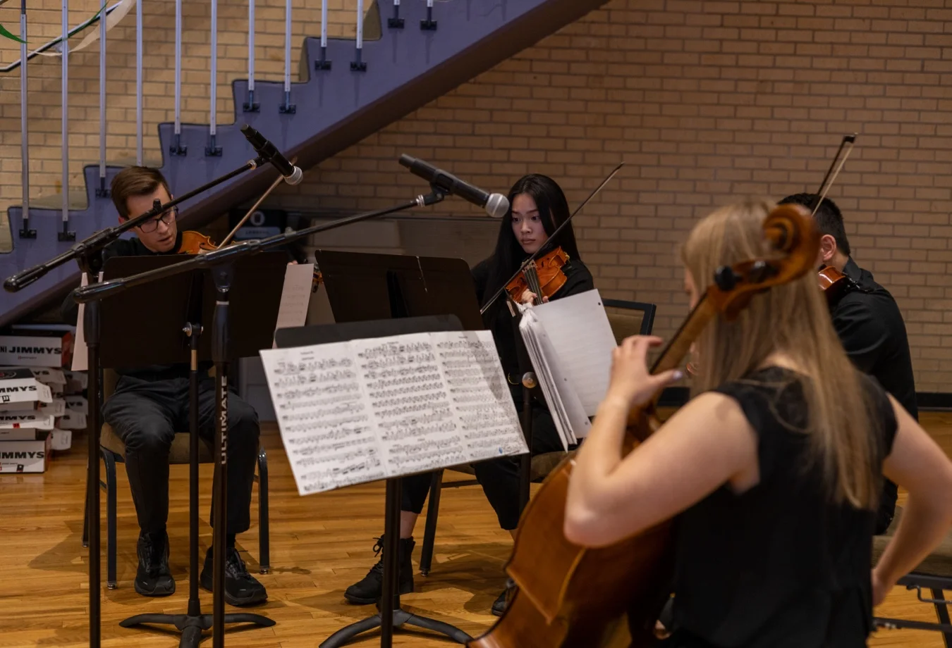 Mines student string quartet performing together in a large room.