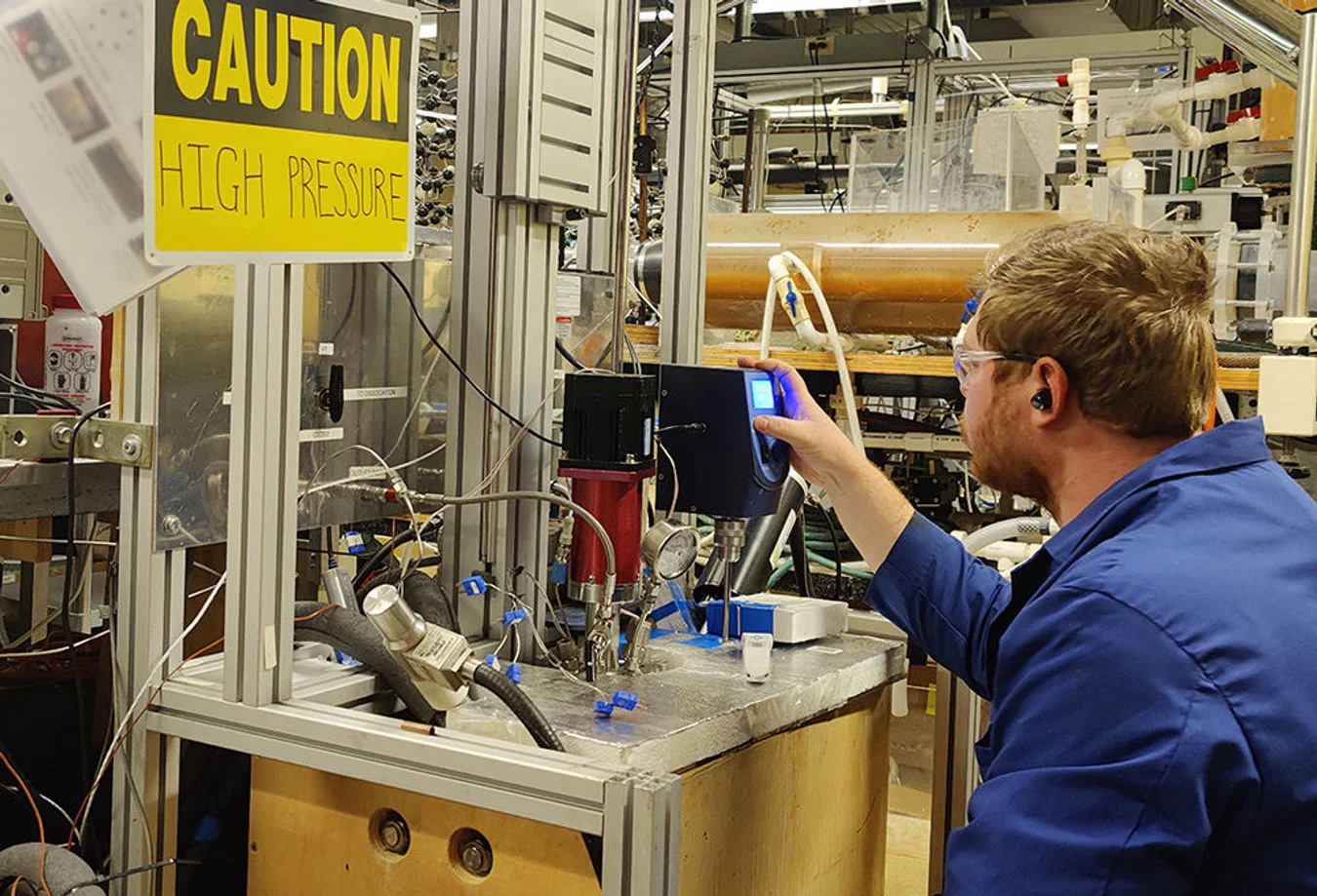 A man in a blue shirt is working on a machine.