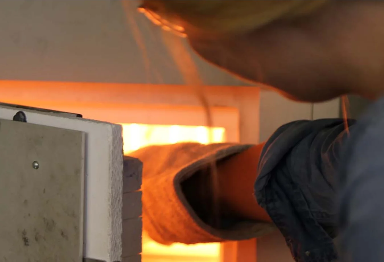 a woman working on a piece of metal in a furnace.