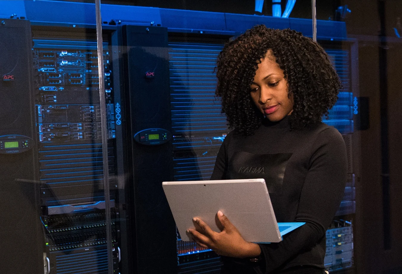 A woman using a tablet computer in a server room.