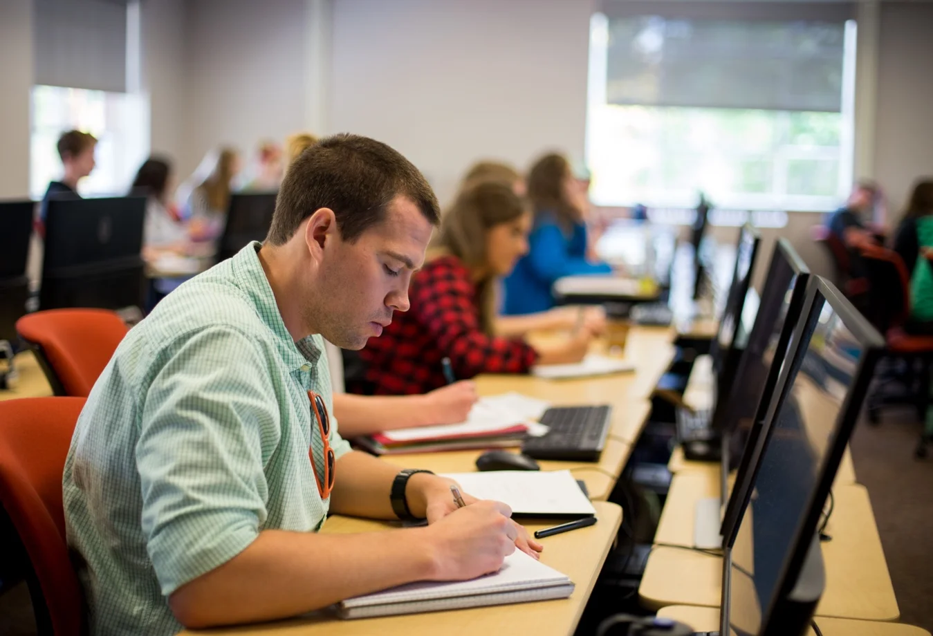 A male graduate student taking notes in during a lecture in the classroom