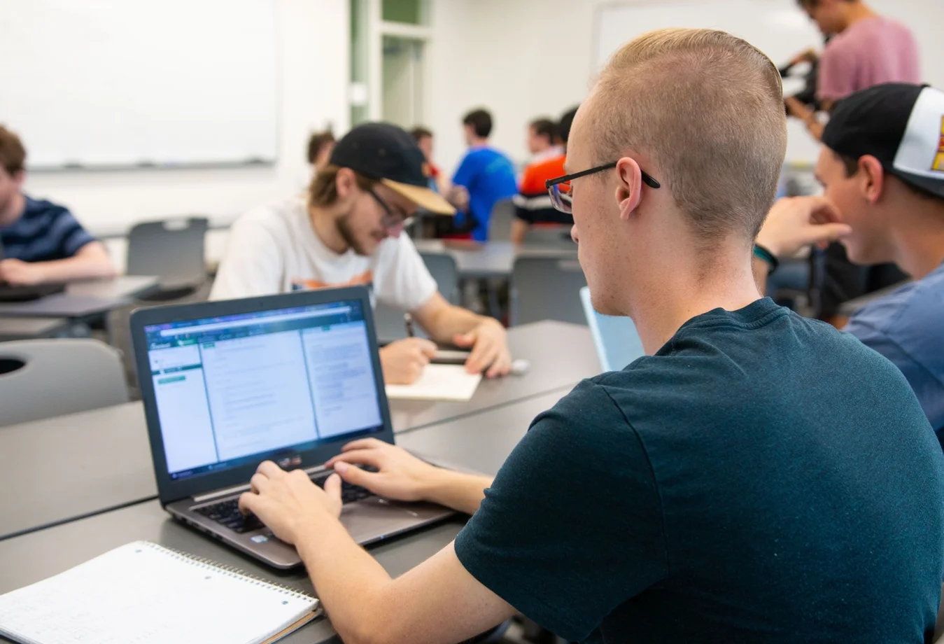 A male Mines student working on a laptop in the classroom.