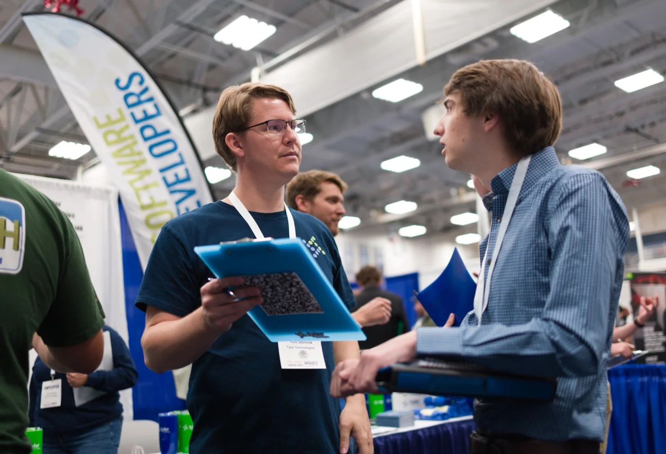 A male student speaking with a male respresentative during a conference or career fair.