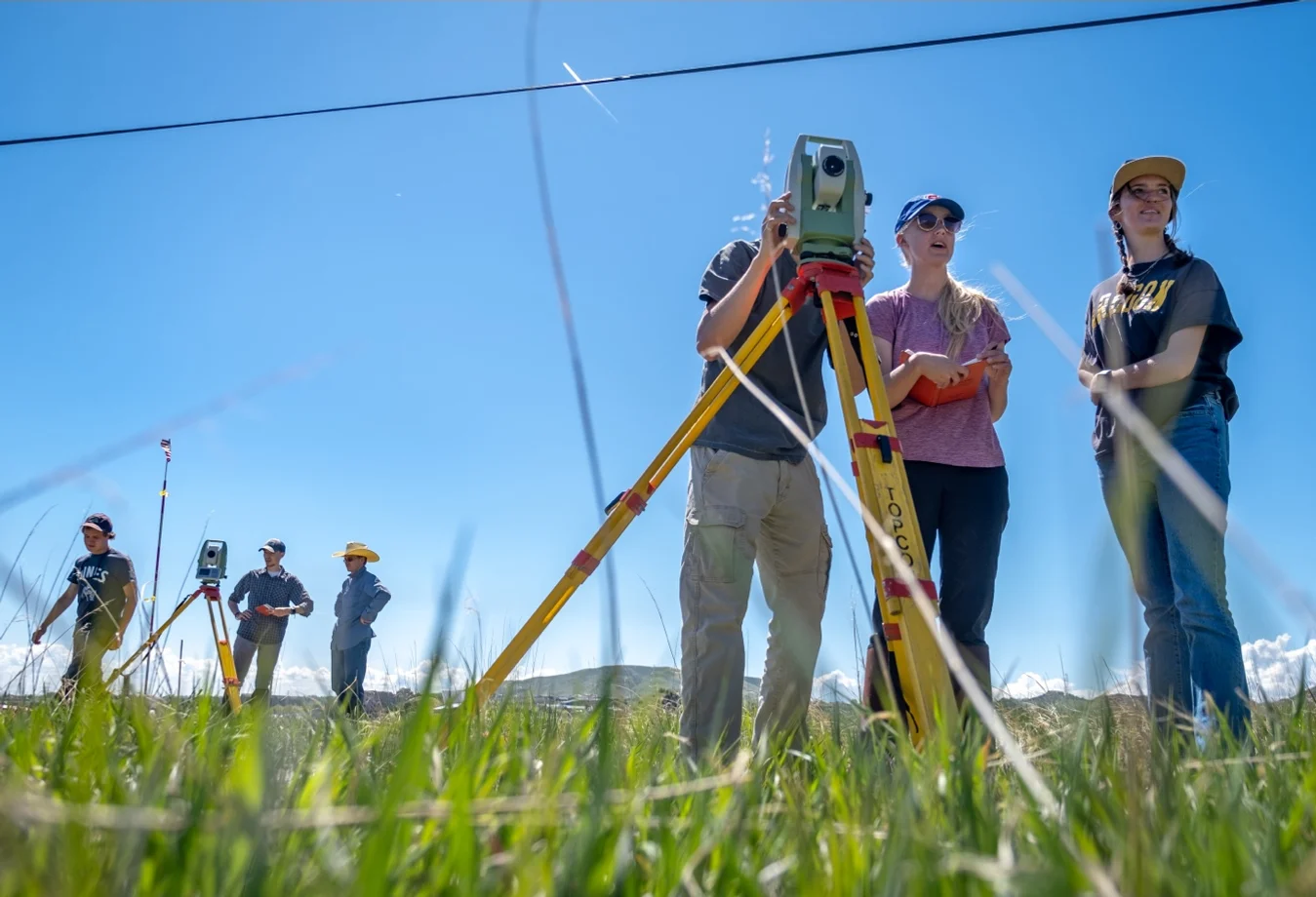 shows students gaining hands-on experience using a Total Station for a civil engineering field session