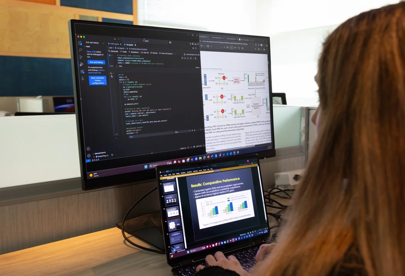 Female student working on laptop connected to a desktop monitor.