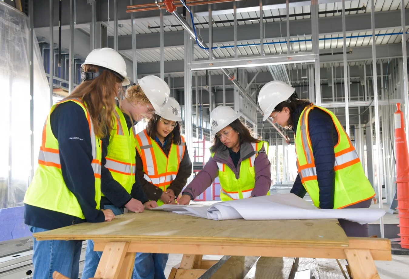 Mines students at a construction site reviewing blue prints with their professor.