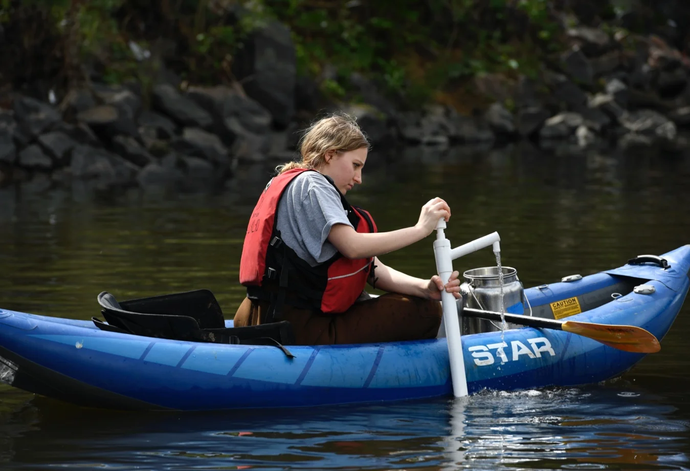 A Mines student sitting in a STAR Raven inflatable kayak, testing the self-bailing pumping system.