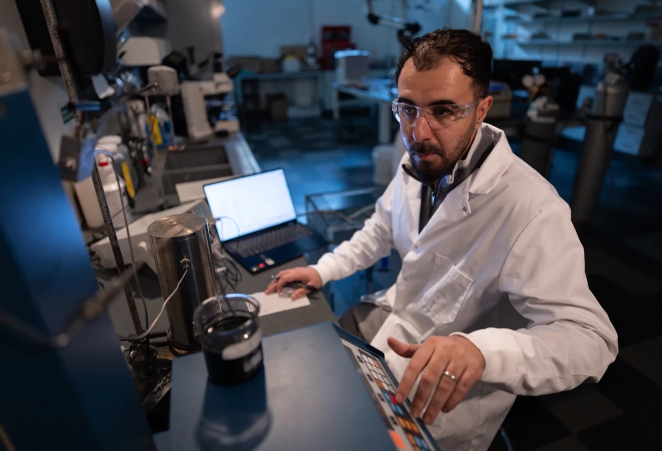 A researcher in a white lab coat meticulously operating laboratory equipment