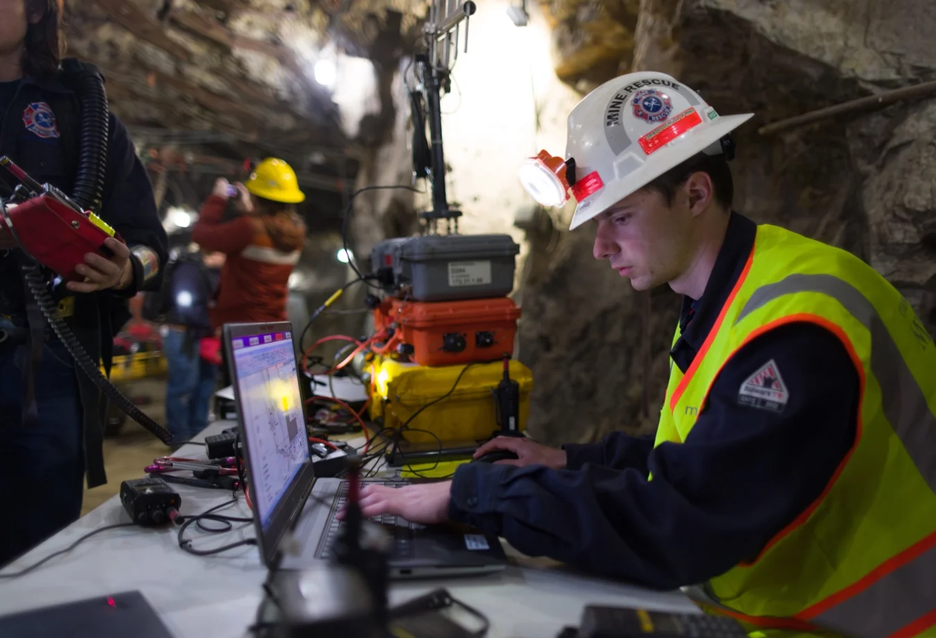 A student monitoring data on a laptop in a mine, running test on of seismic activity