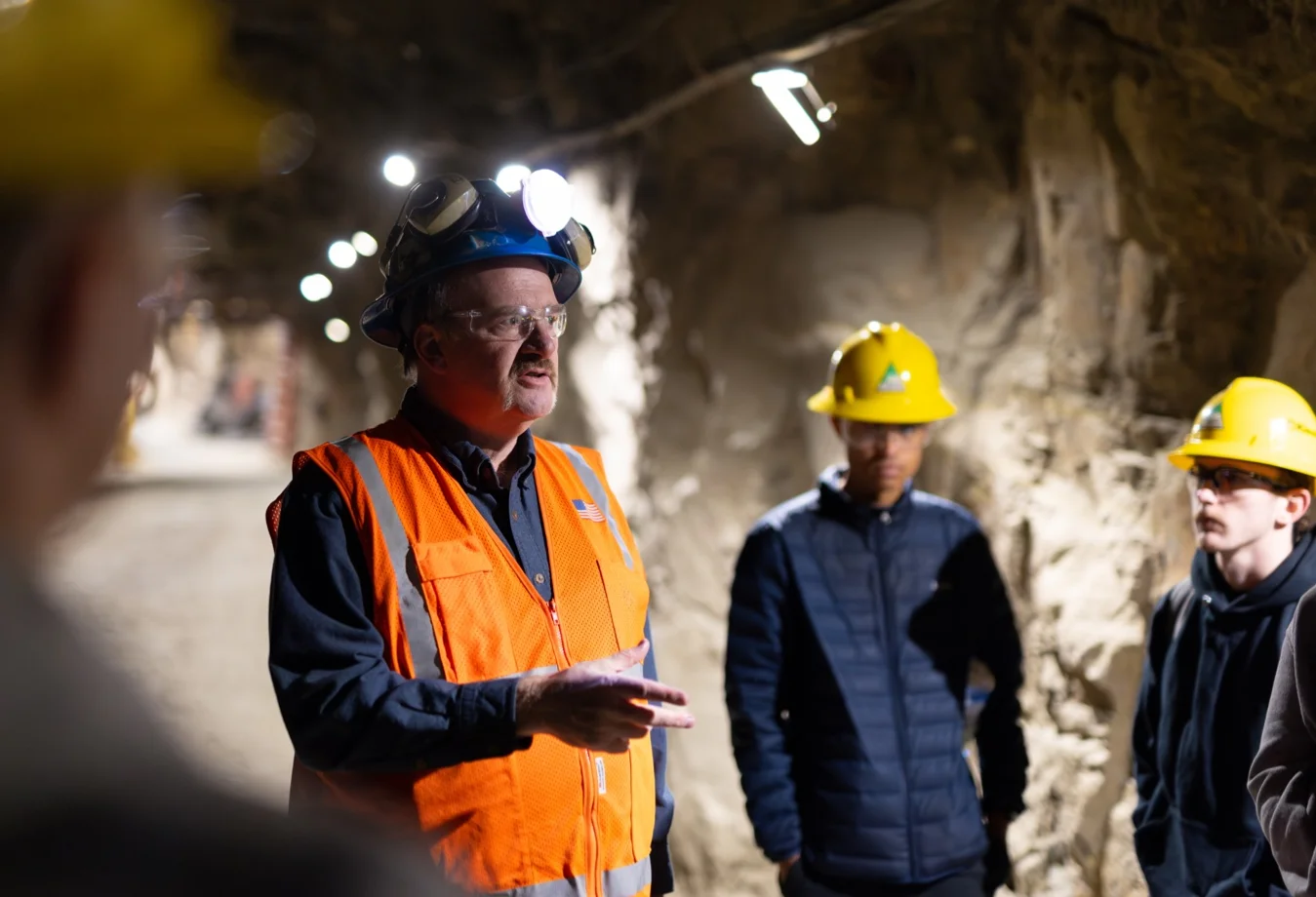 A group of people receiving training in an underground mining tunnel.