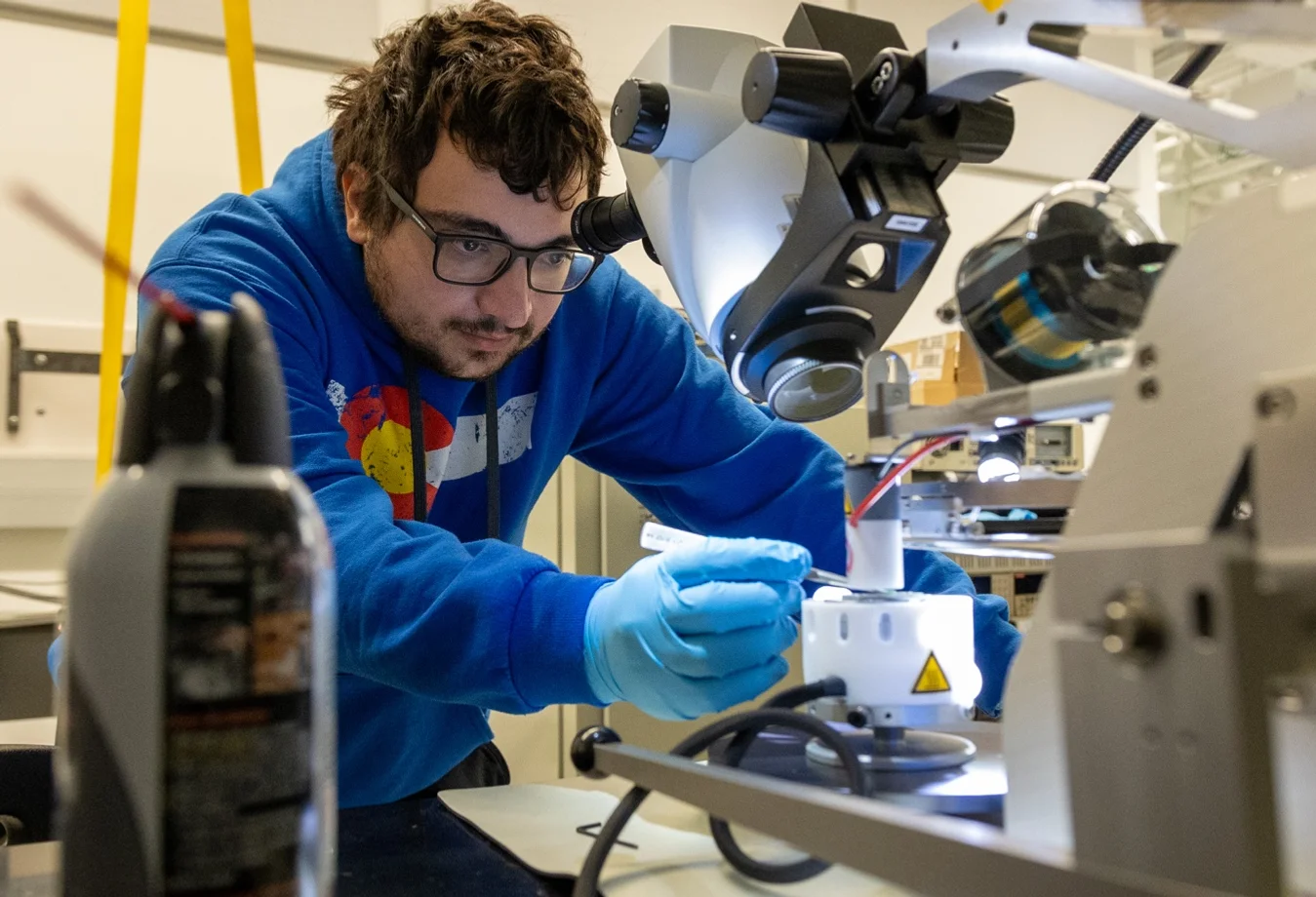 Quantum Engineering student working intently at a microscope in a laboratory setting.