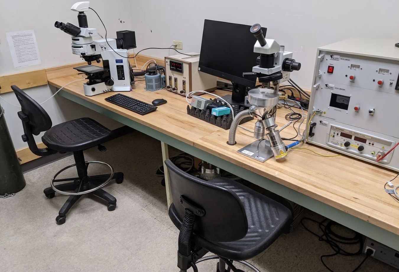 A desk with two microscopes and a computer on it.