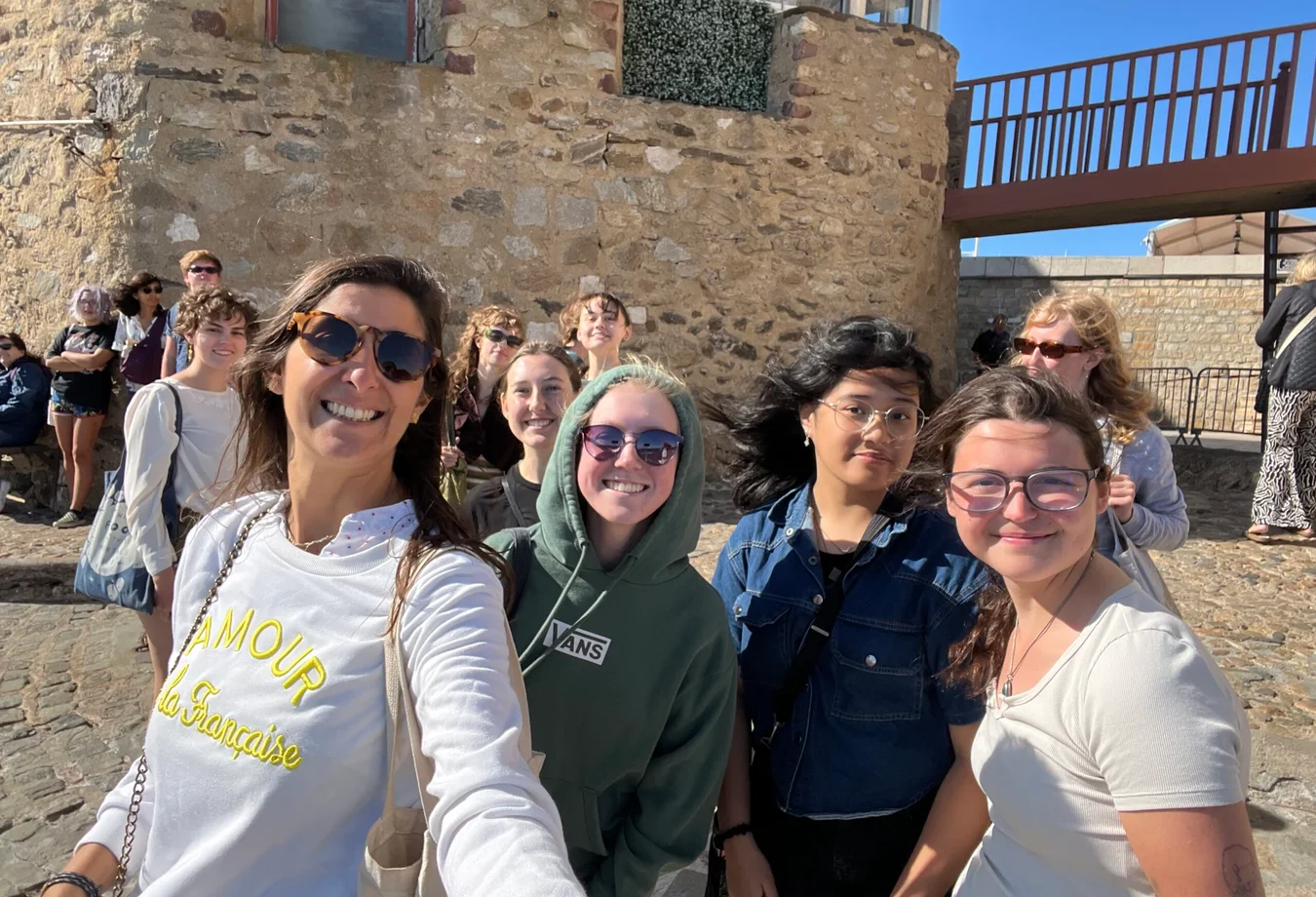 A group of women smiling and taking a selfie in front of a colorful building in St. Tropez.