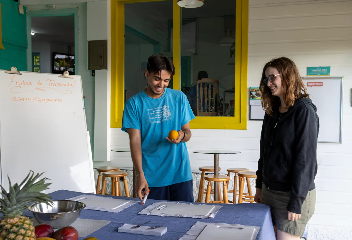 A man and woman stand together in front of a table, smiling during their Spring Break study abroad trip in Costa Rica.