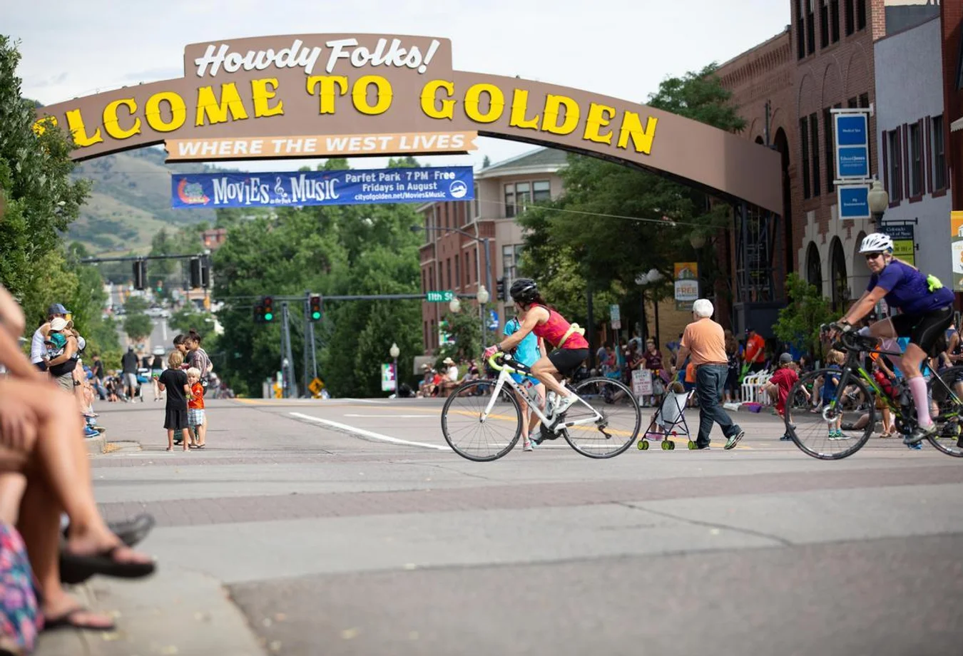 Cyclists ride through a street in Golden under a 