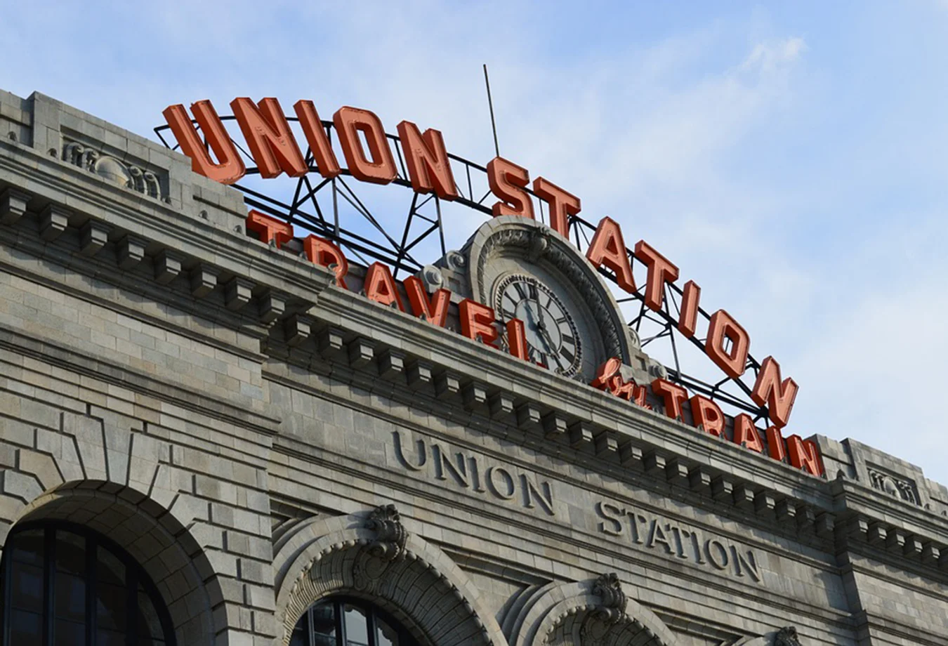 Historic Denver Union Station building facade with a large clock and bright orange 