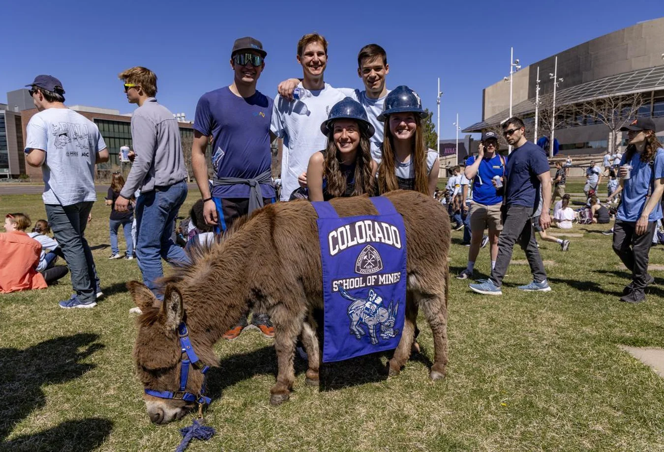 Mines students pose behind Blaster the Burro at E Days Ore Cart Pull to the capitol.