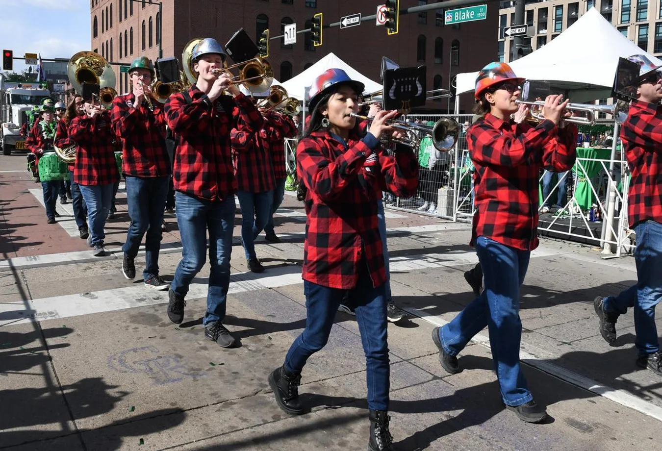 Mines Marching Band students play instruments in a St. Patrick's Day parade in Denver.