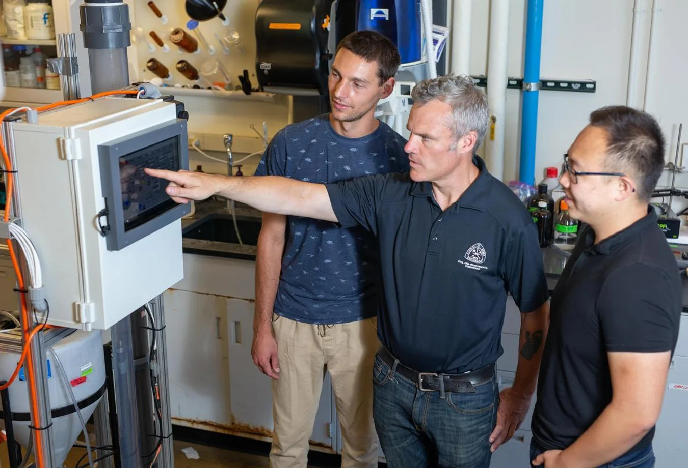 An environmental engineering expert from Colorado School of Mines explains a PFAS eliminating machine to students.