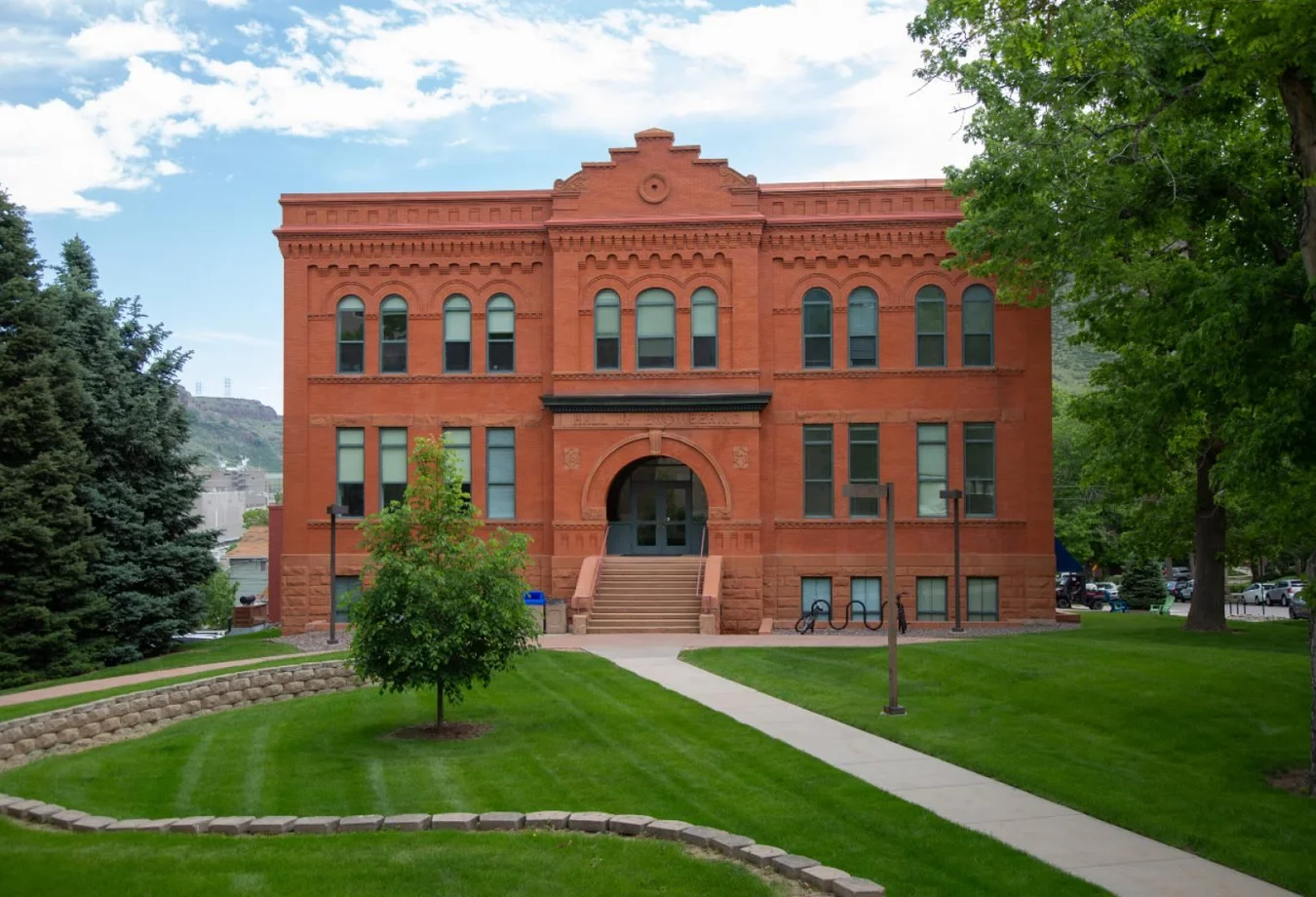 A large red brick building sitting on top of a lush green field.