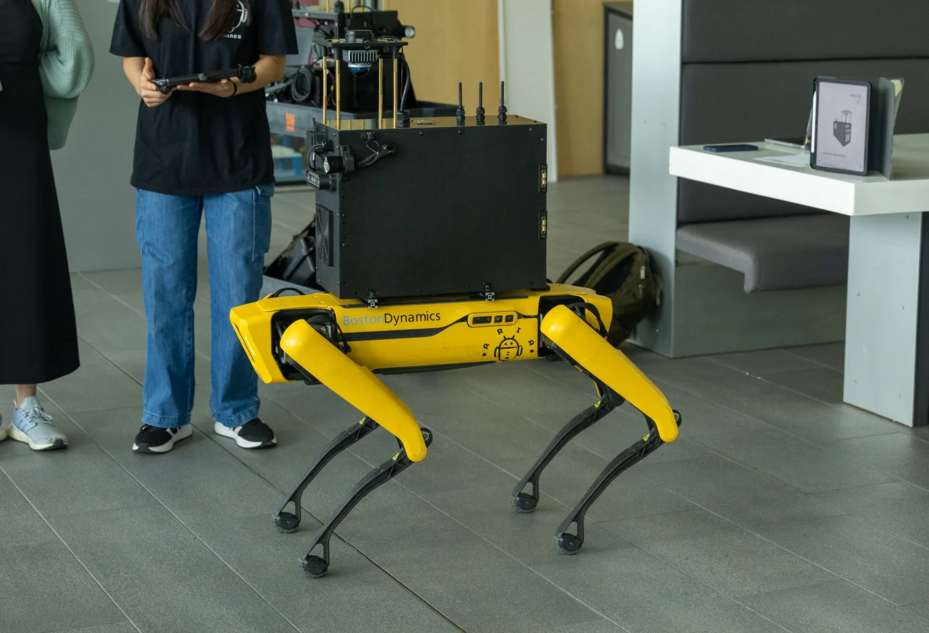 A woman standing next to a yellow and black robot.