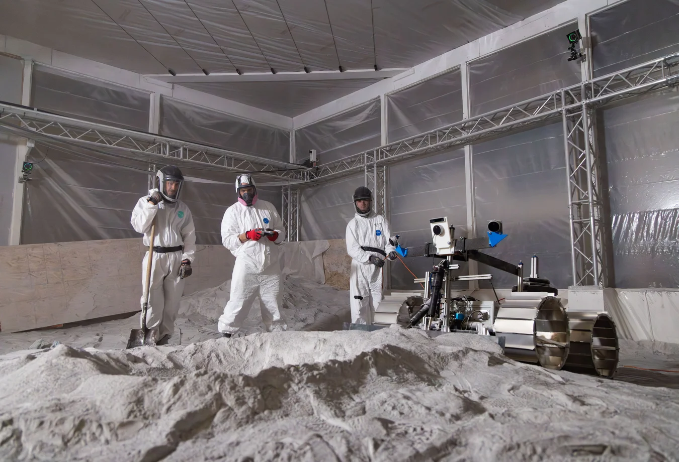 A group of men in white suits standing in a room filled with sand.