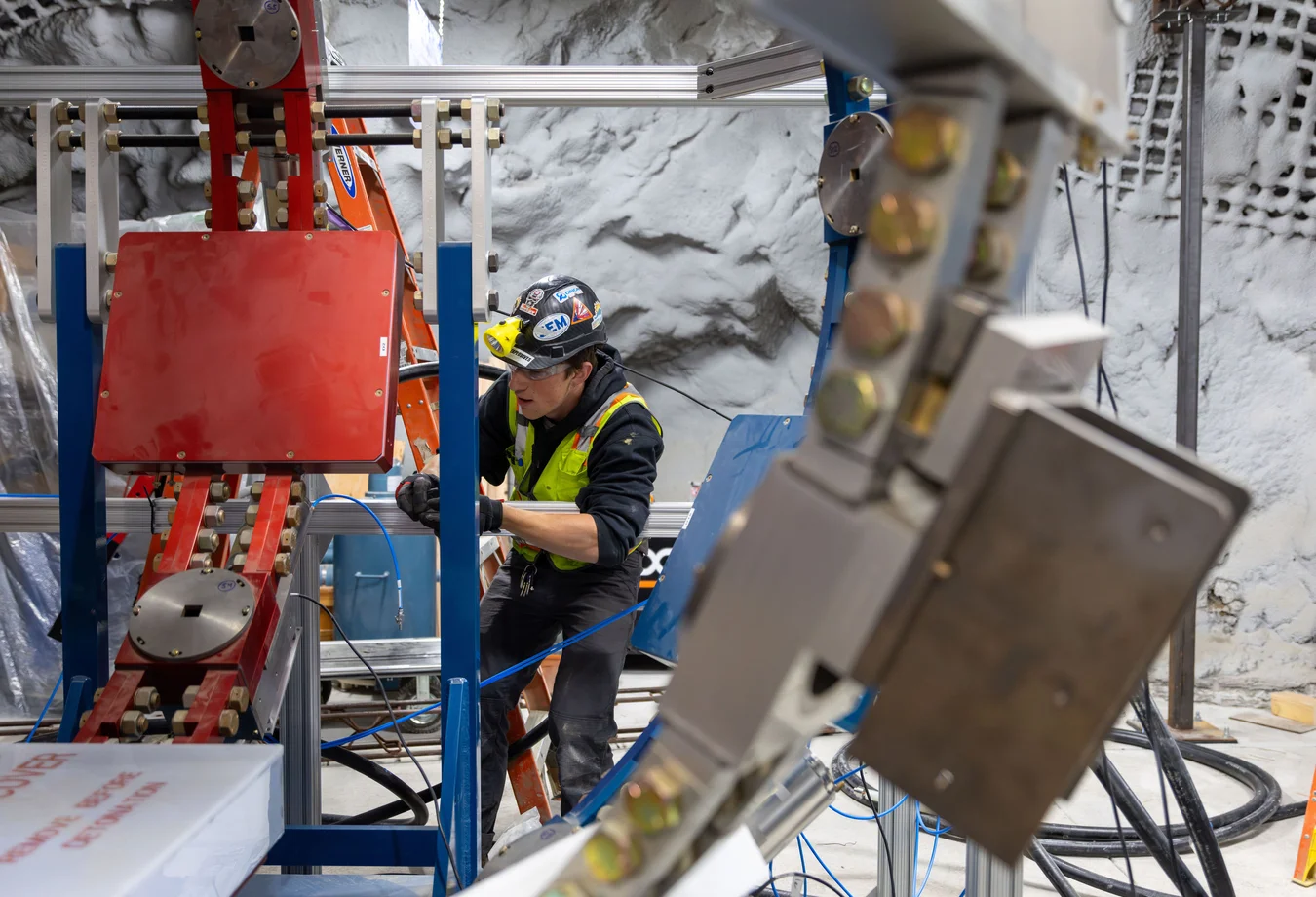 A man in a hard hat and safety vest working on a machine.