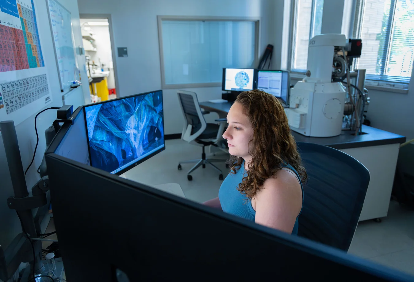 A woman sitting at a desk in front of two computer monitors.