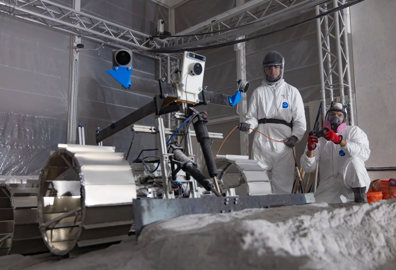 Two men in protective gear working on a machine.