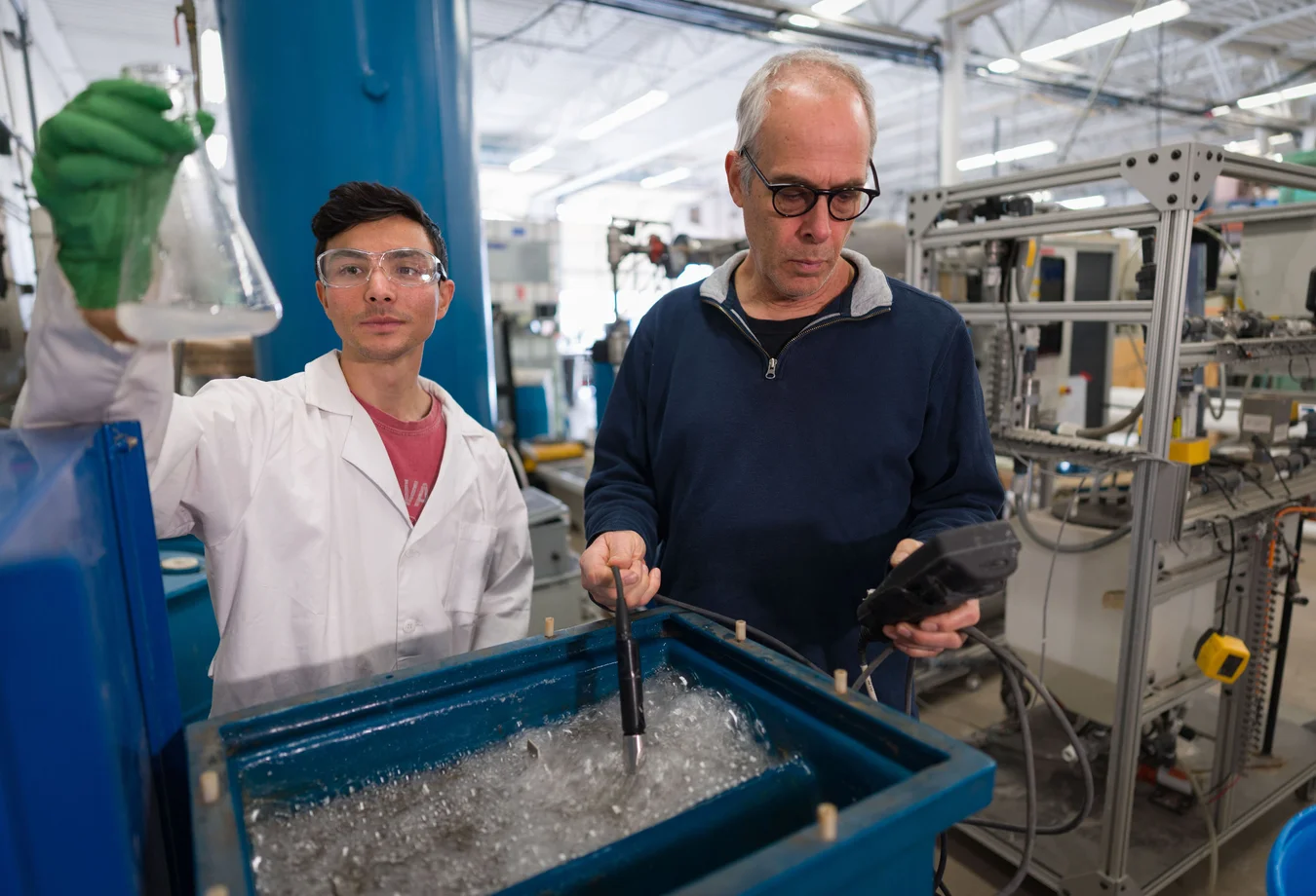 Two men in lab coats working in a factory.