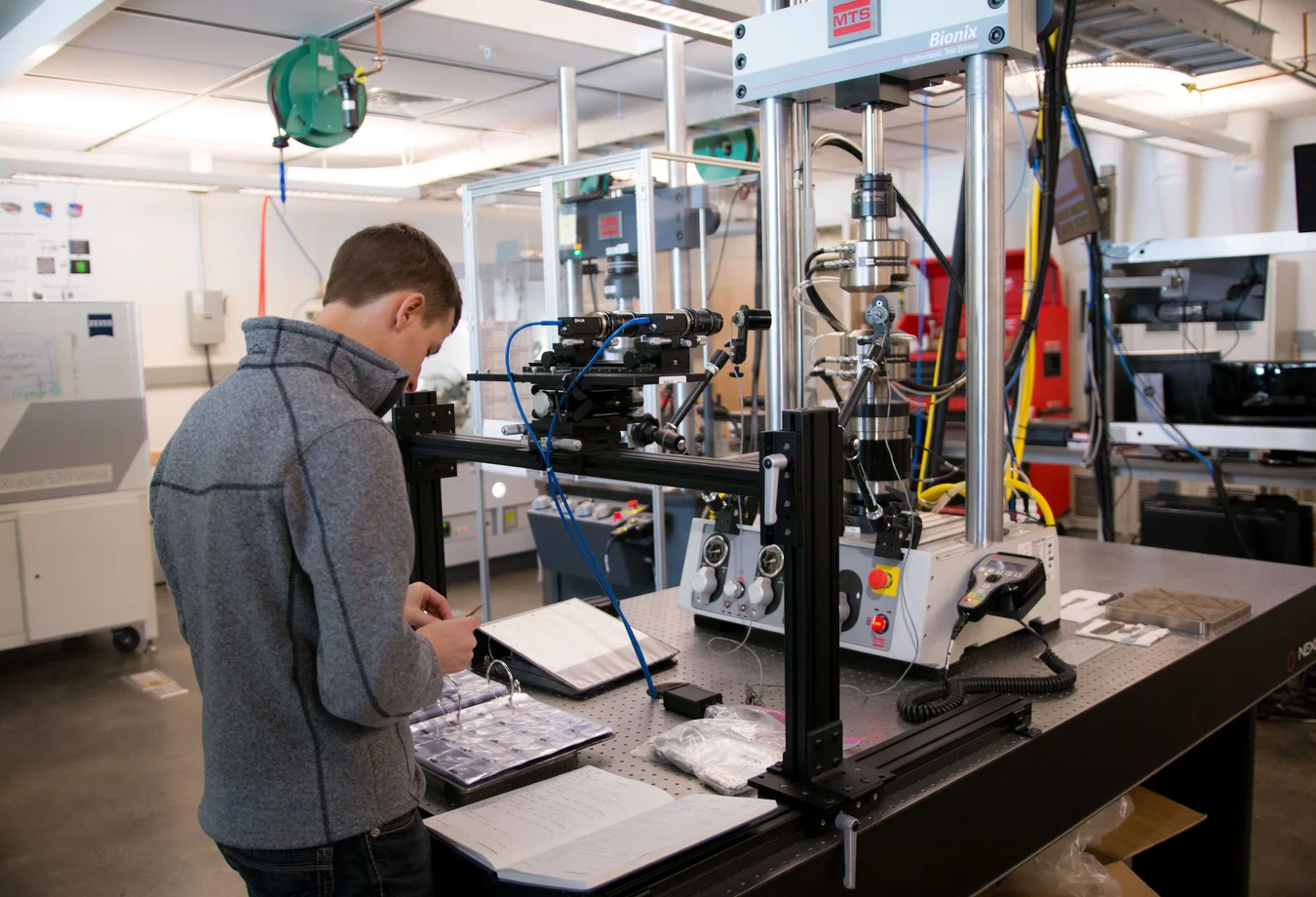 A man standing in front of a machine in a lab.