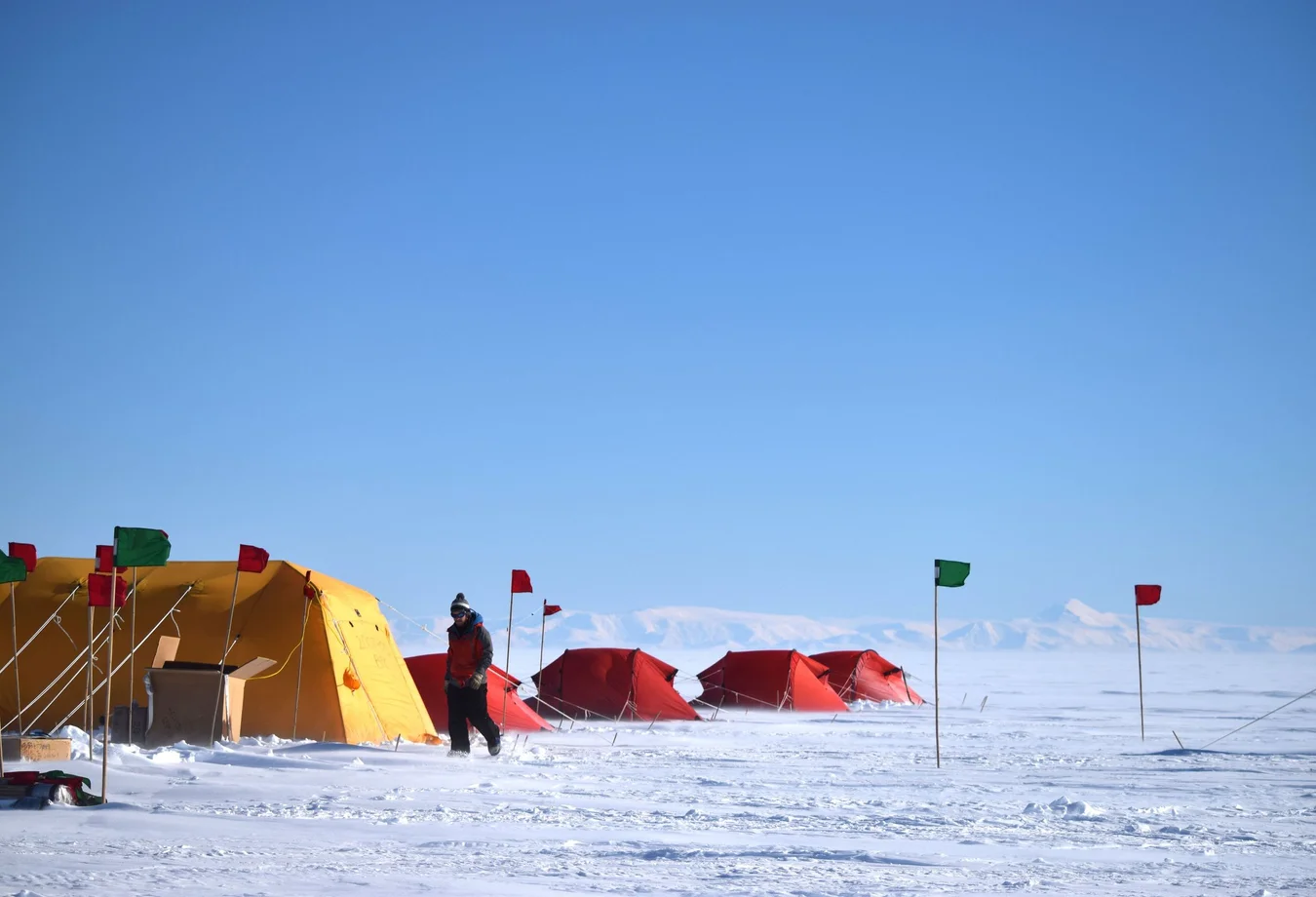 A group of tents in the middle of a snow covered field.