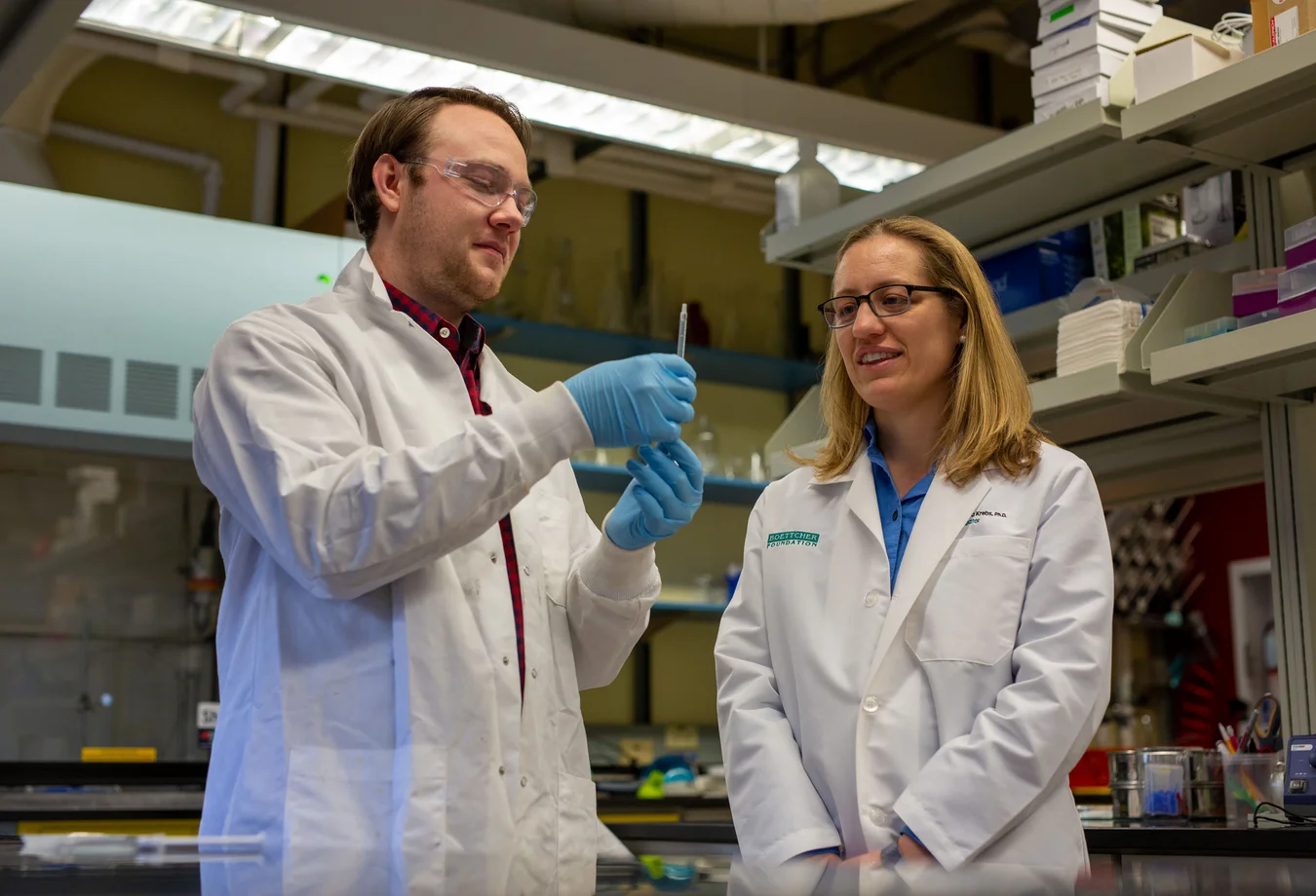 A man and a woman in lab coats looking at something.