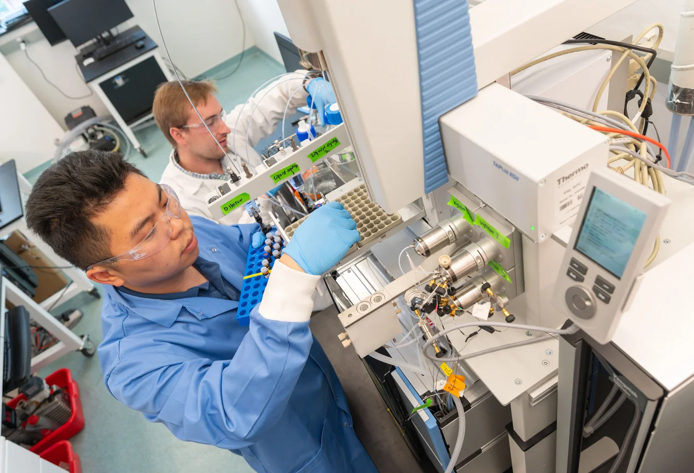A man in a blue shirt and blue gloves working on a machine.