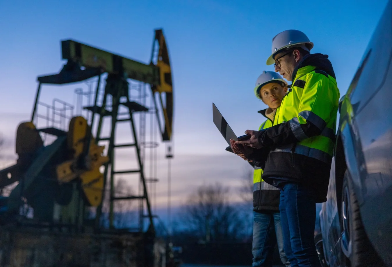 Field professionals working with laptops to survey the progress of the oil field.
