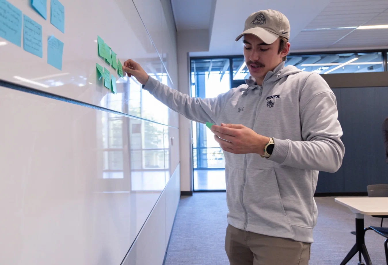 Mines student placing post-it notes on whiteboard
