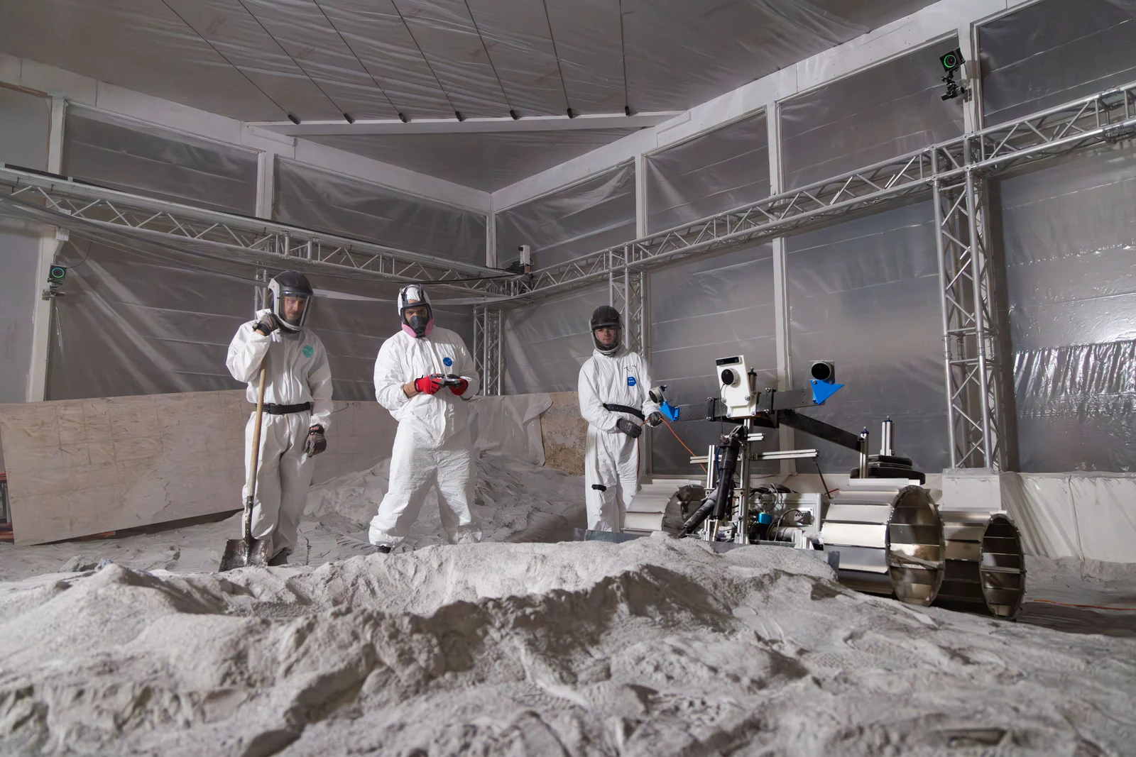 A group of men in white suits standing in a room filled with sand.